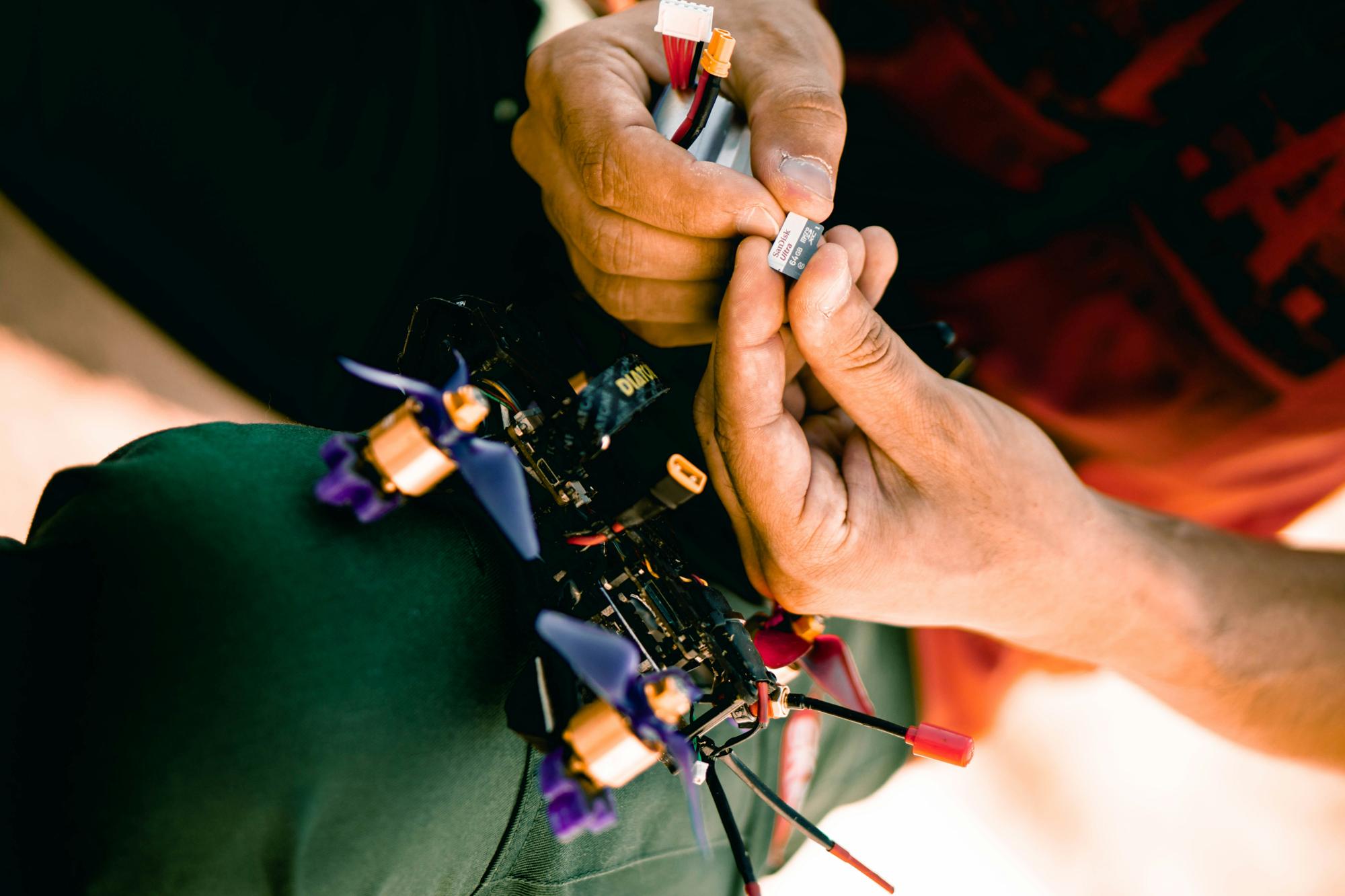 Hands assembling a small racing drone